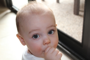 Evie Lattimore, 1 year old sitting on floor sucking her thumb