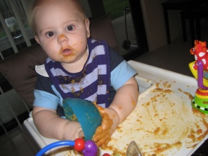 Hugo Lattimore playing with his food in a high chair making a spectacular mess