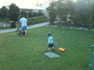 Hugo helping mow the lawn with toy plastic mower