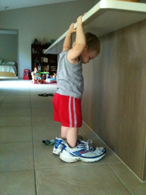 Hugo Lattimore at 17 months of age, standing with his feet in his fathers running shoes